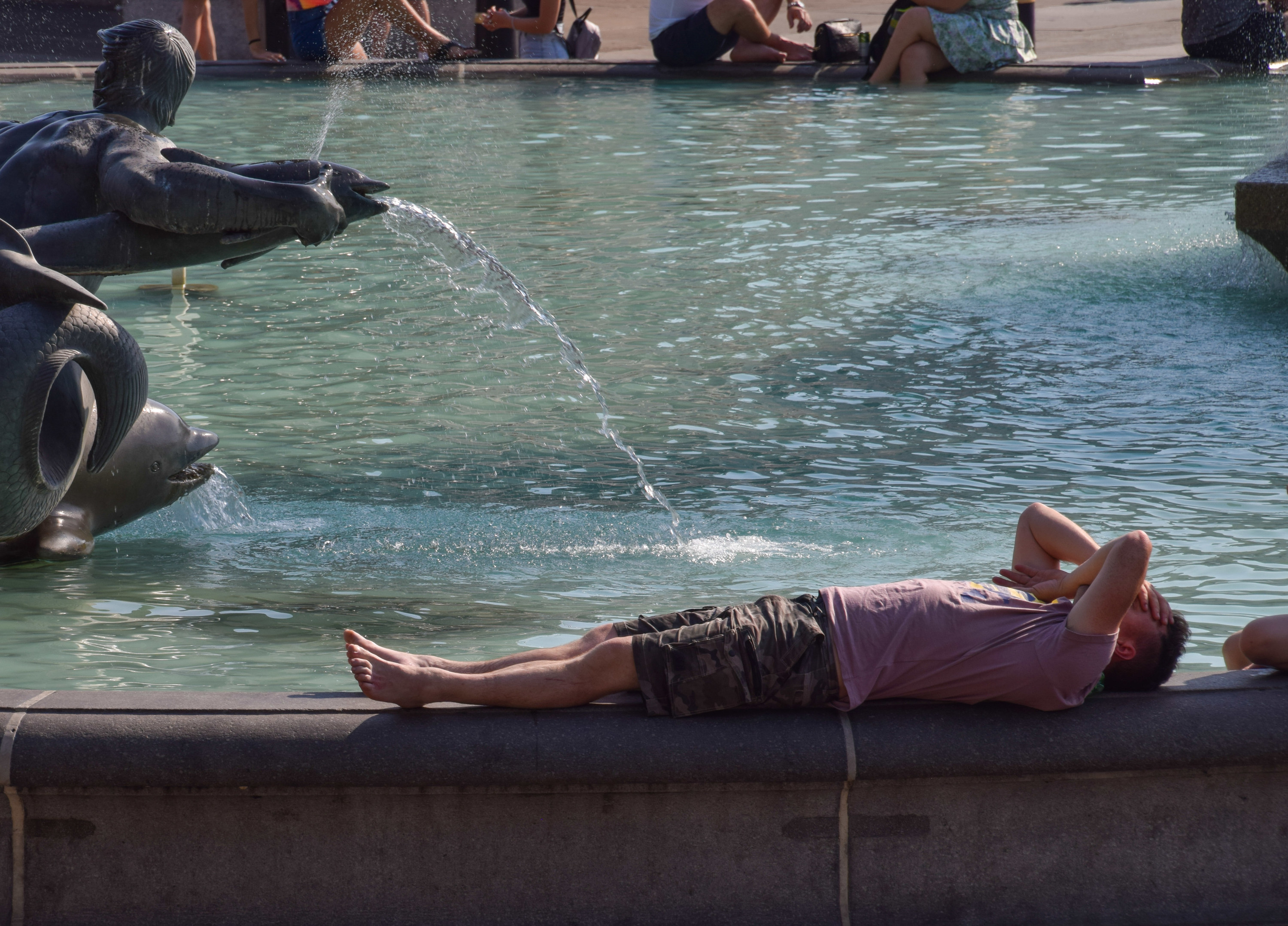 A person trying to cool off at a fountain