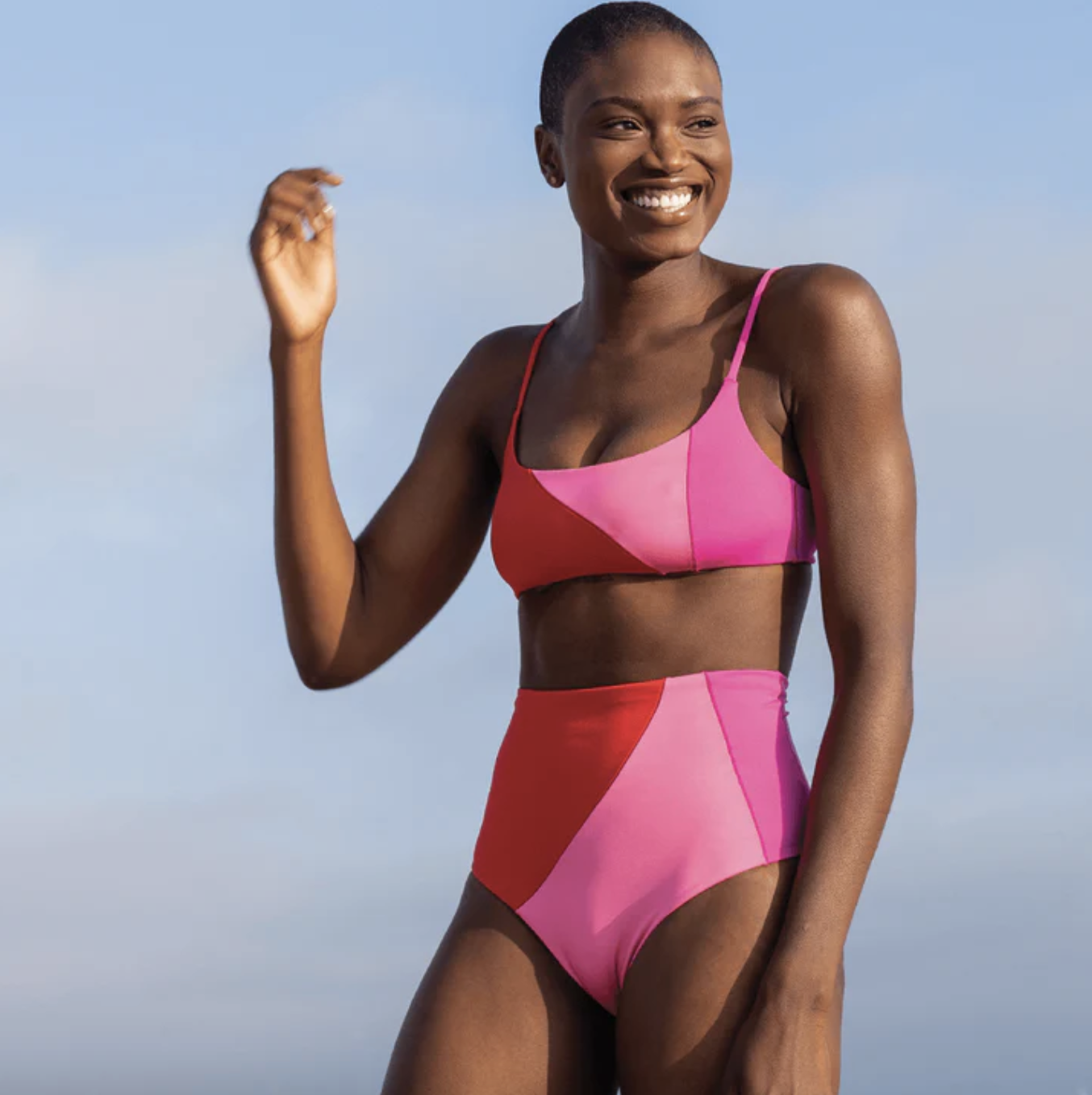 model wearing the suit with high waisted bottom and spaghetti strap top with colorblocks of pink and red