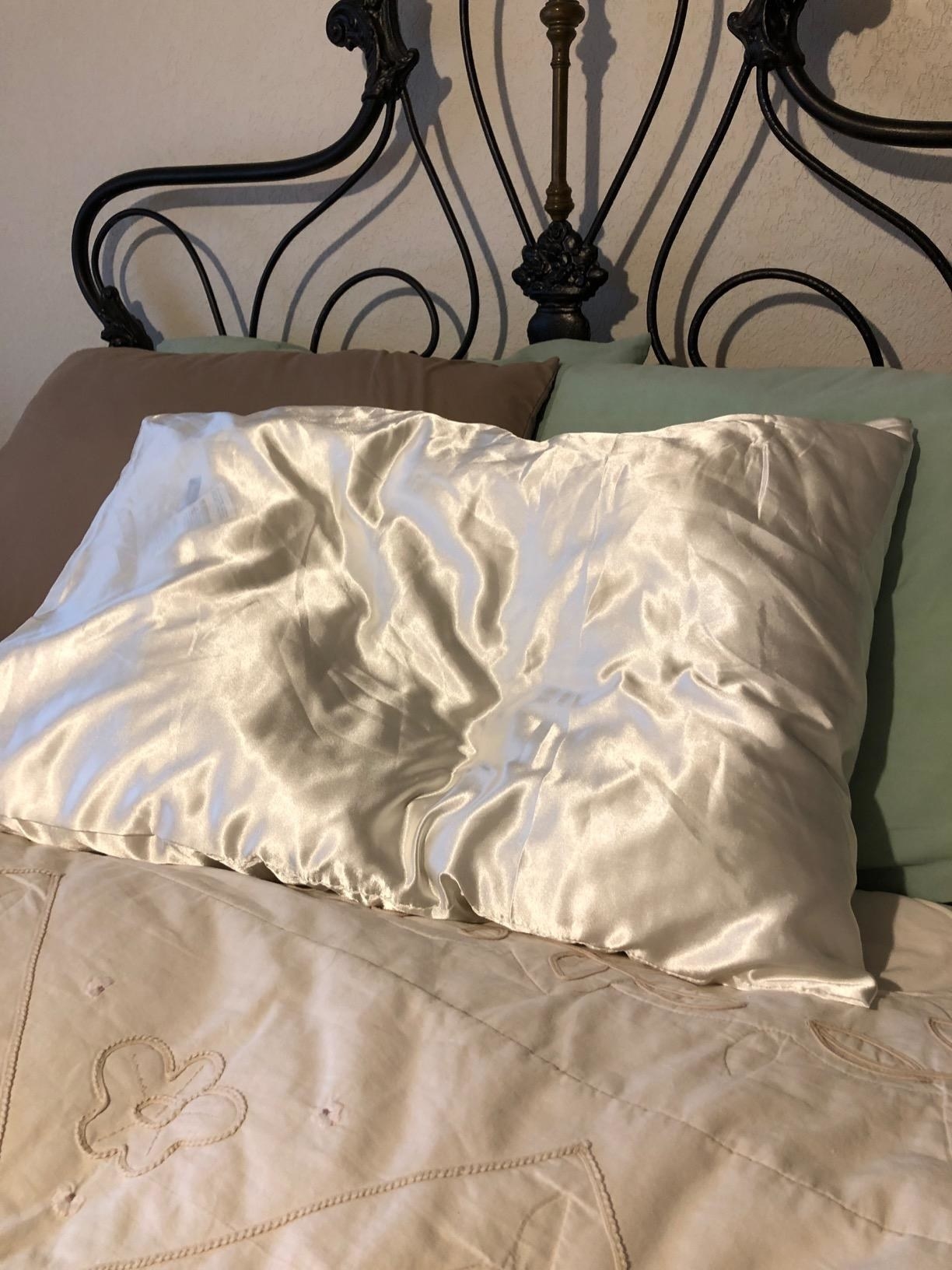 a reviewer photo of the satin pillowcase on their bed