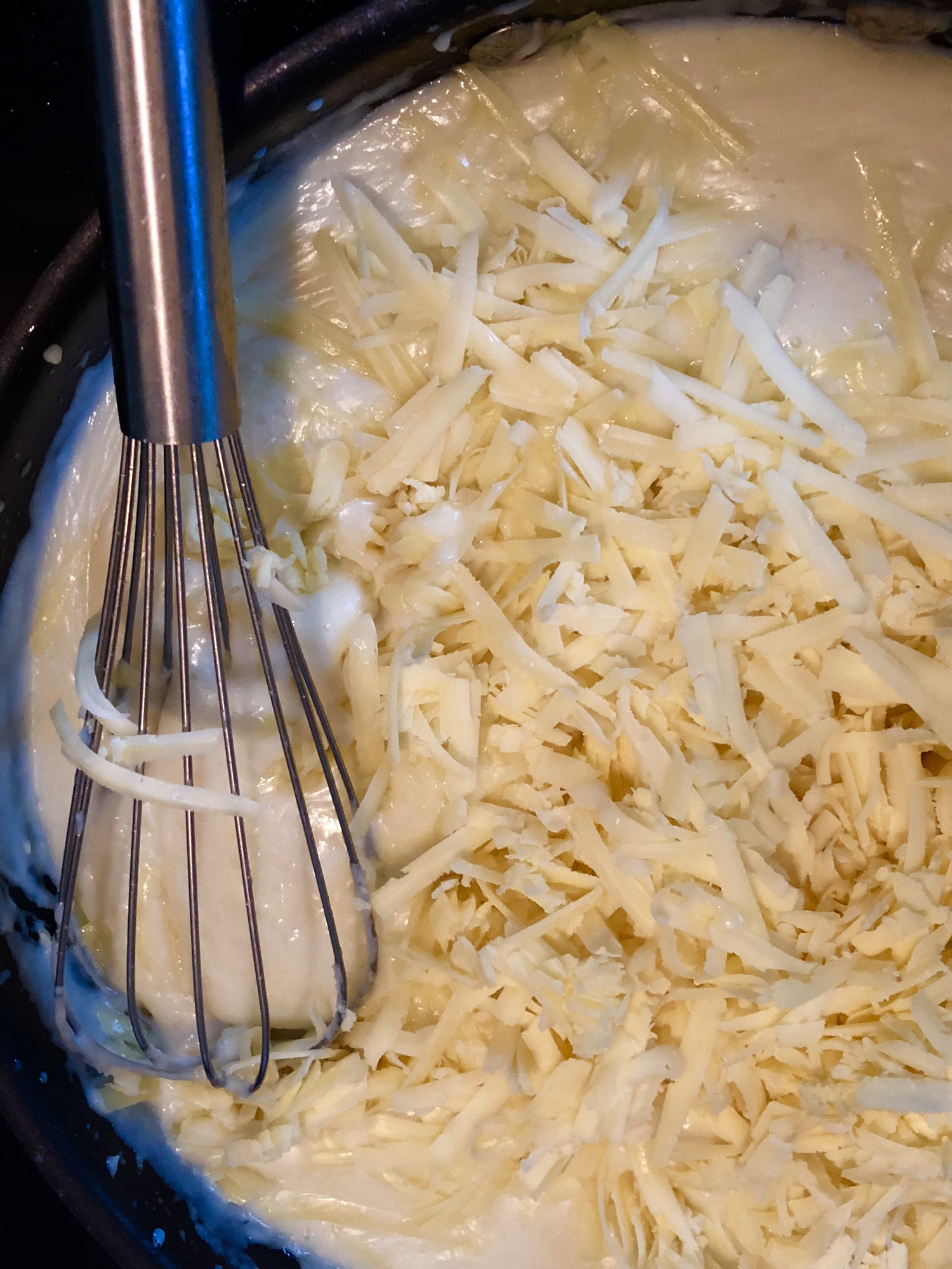 Stirring a white sauce with grated cheese.