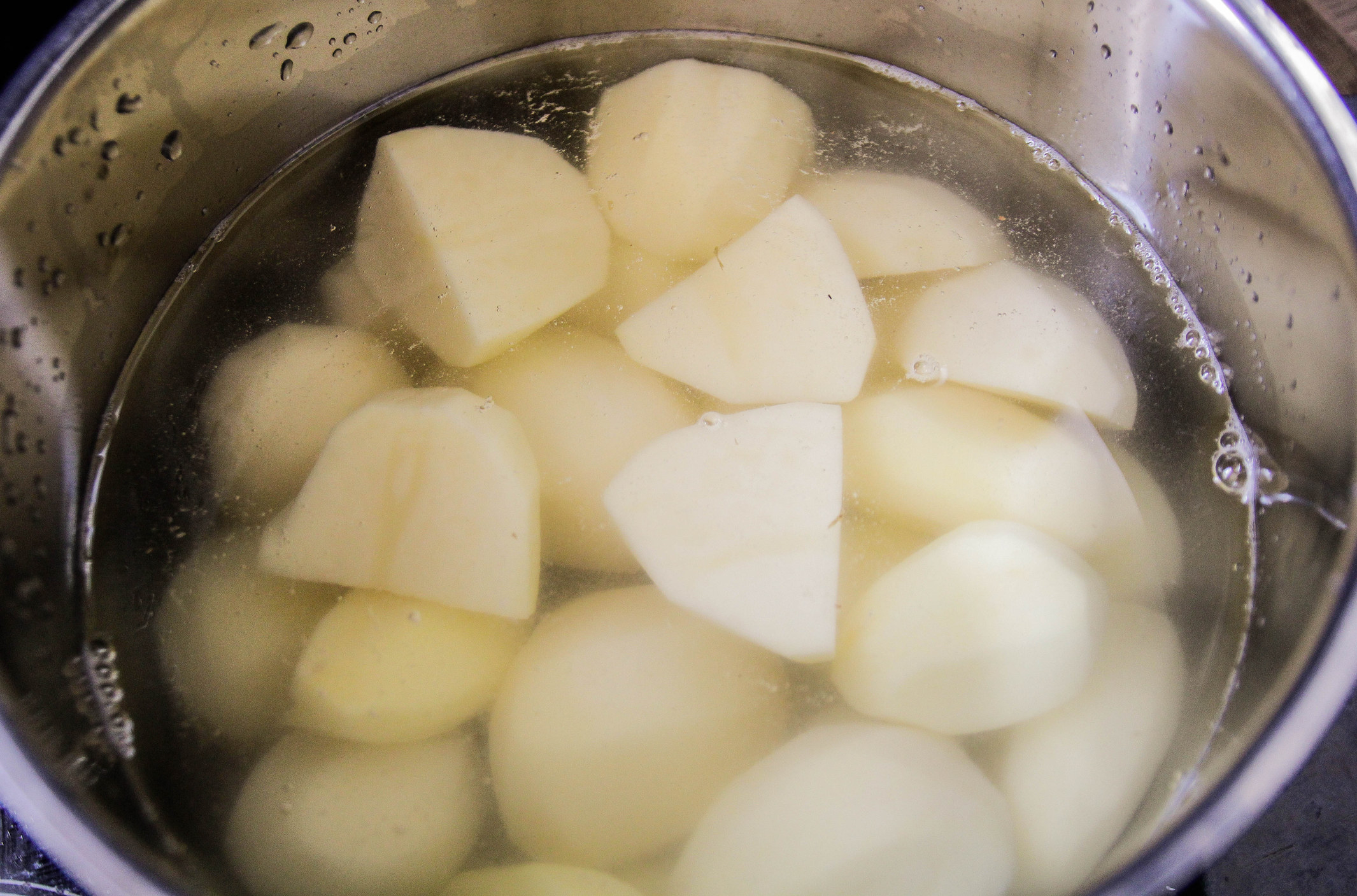Boiling baked potatoes in a pot of water.