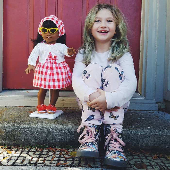 little girl with her American Girl doll sitting on her front step