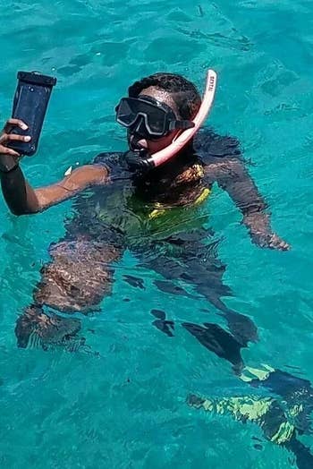 person snorkeling using their phone inside the case while in the water