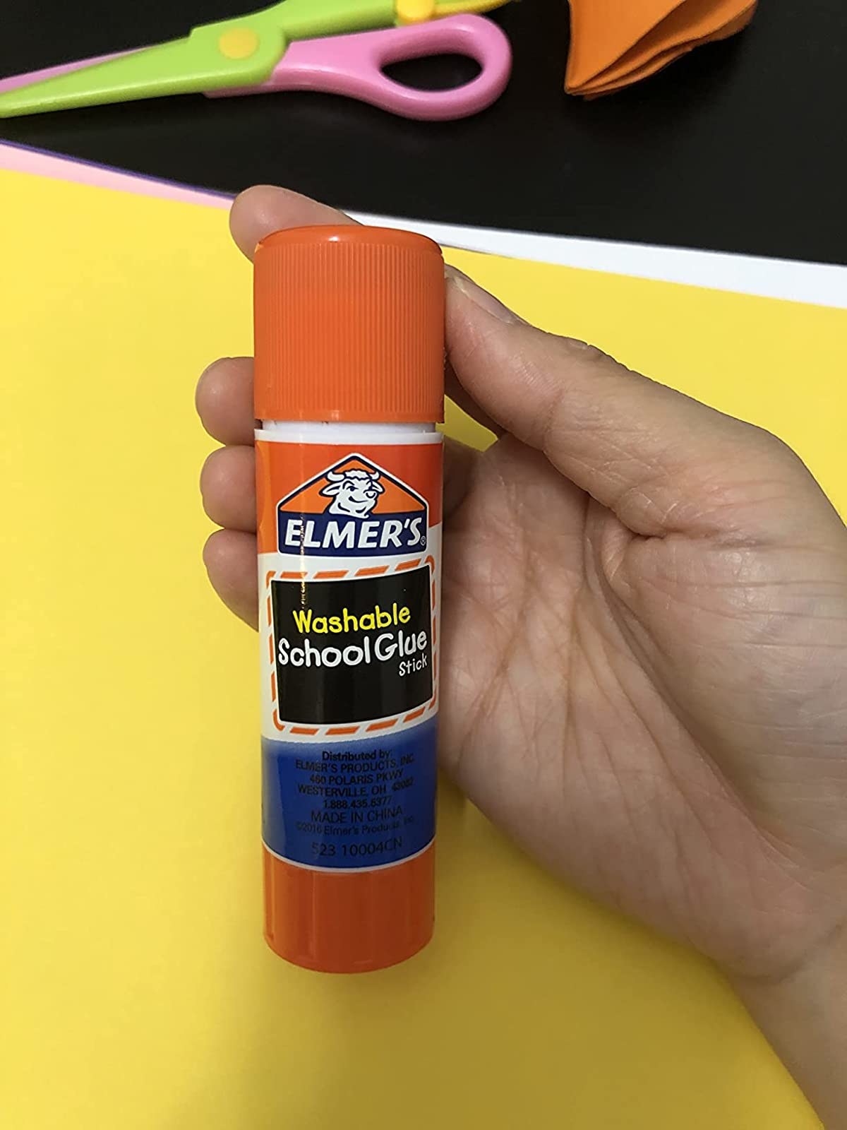 Reviewer holding the giant glue stick in hand