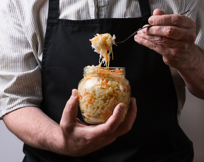 someone scooping sauerkraut out of a jar