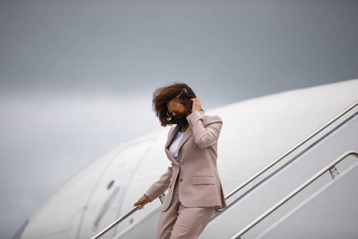 Kamala Harris wearing a mask and descending a set of airplane stairs