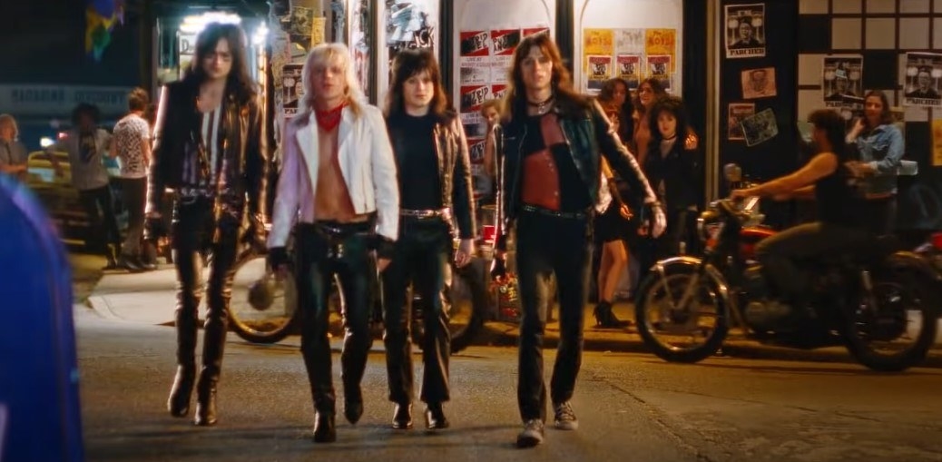 Four actors playing the members of Motley Crue, walking down a street at night, dressed in leather jackets and dark trousers