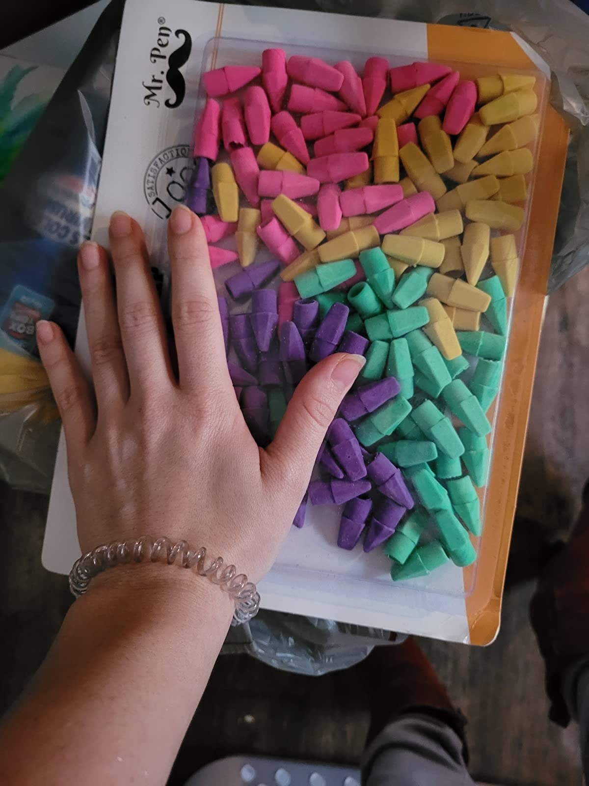 Reviewer with hand neck to package of multi-colored pencil top erasers