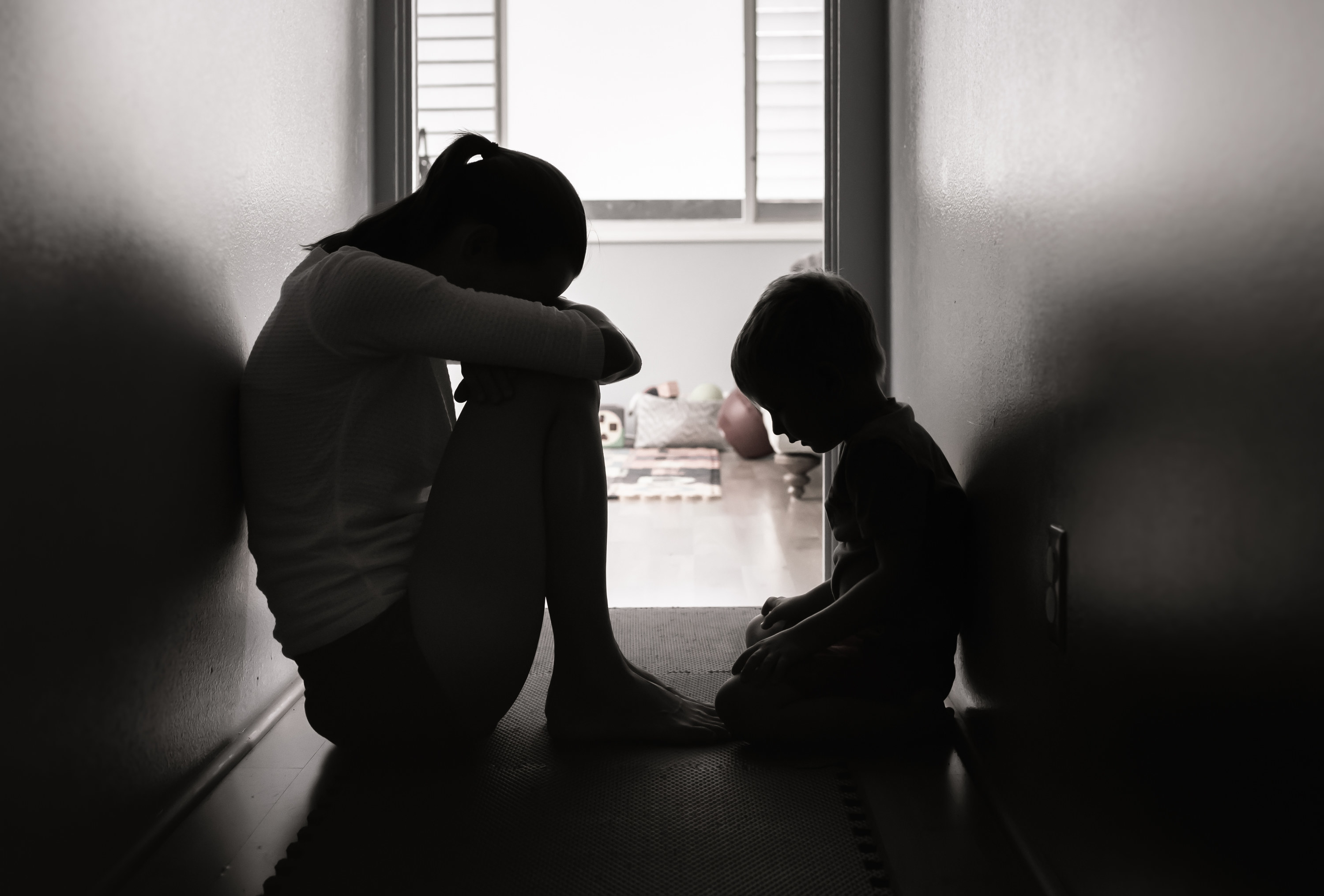 Woman and child looking sad in a dark hallway