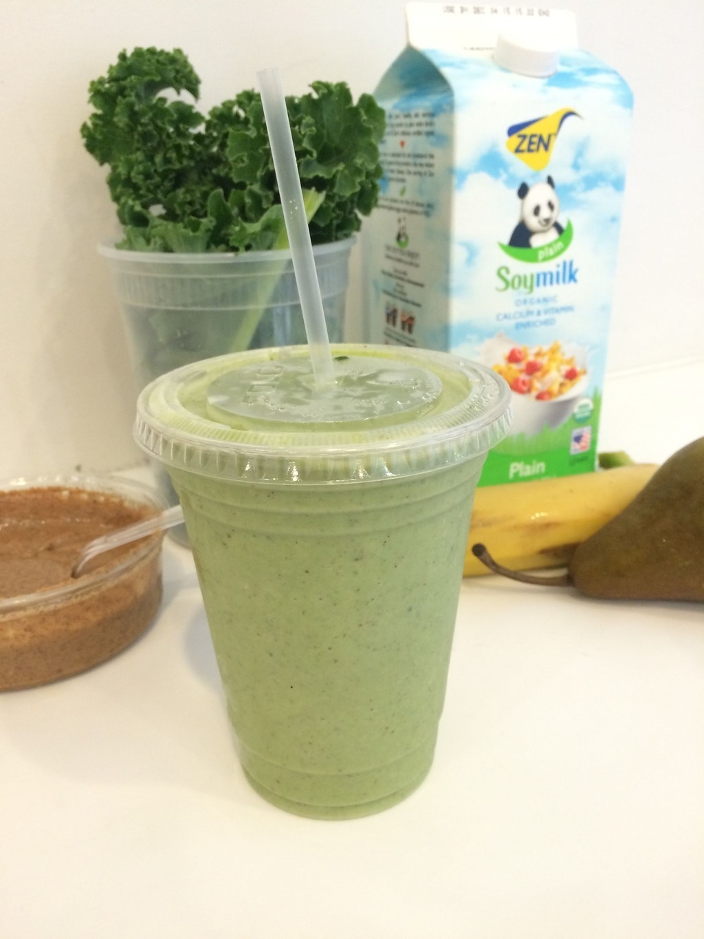 A green smoothie with ingredients in the background.