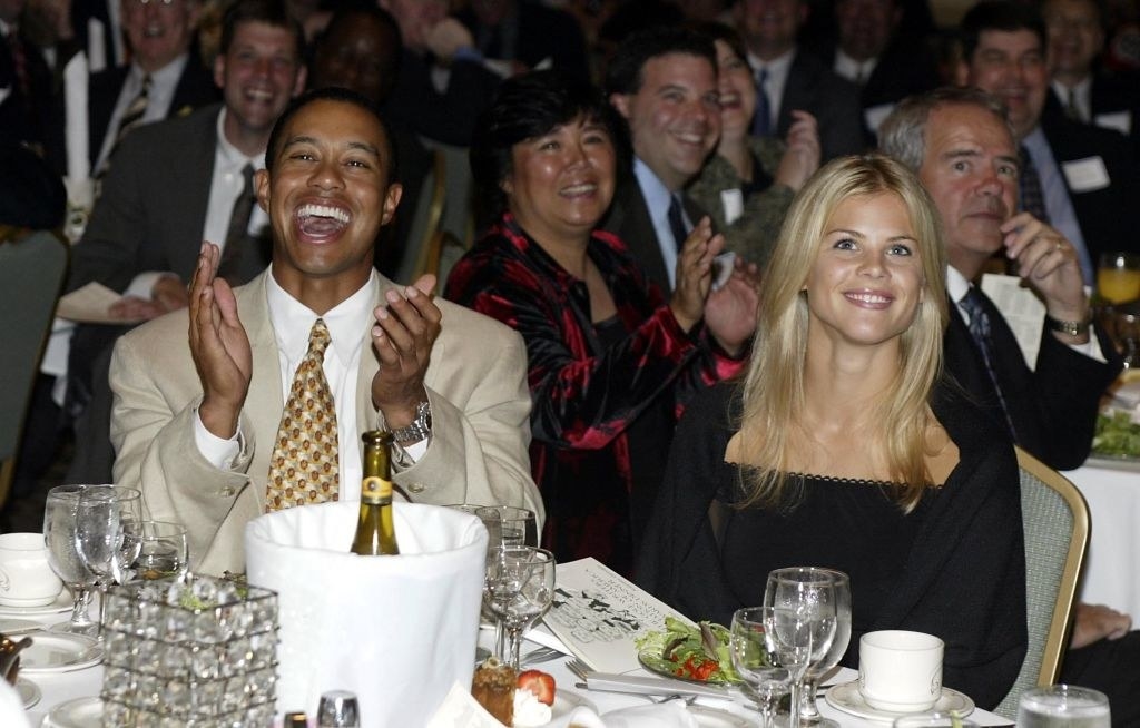 Tiger clapping and Elin smiling while seated at a table