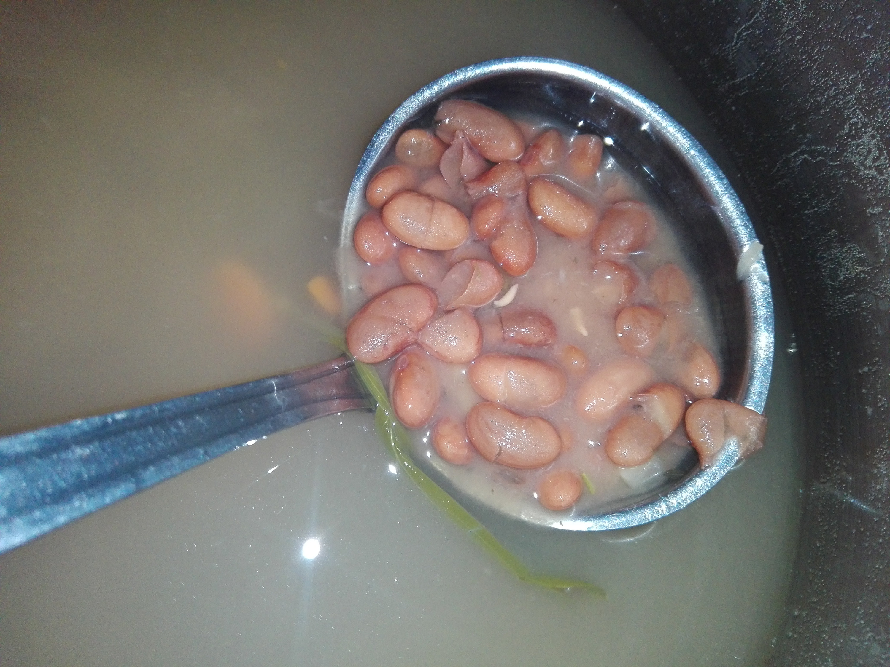 a ladle of cooked beans from a pot