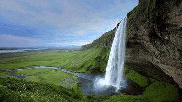 A waterfall spills over a cliff and into a small lake