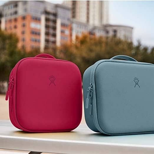 Two lunch boxes sitting on top of a table with the city in the background