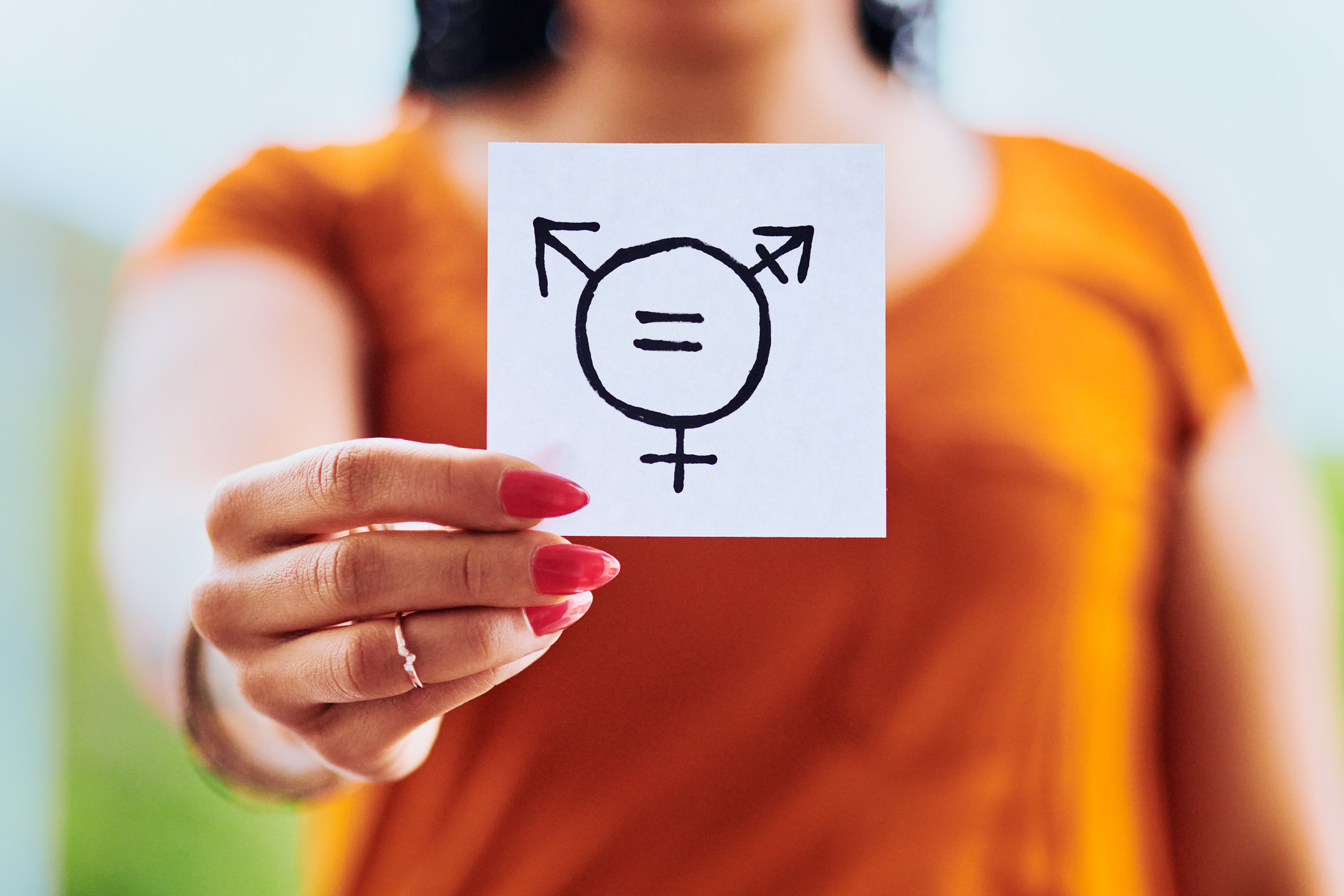 Person holding up drawing of transgender symbol with male, female, and combined symbols