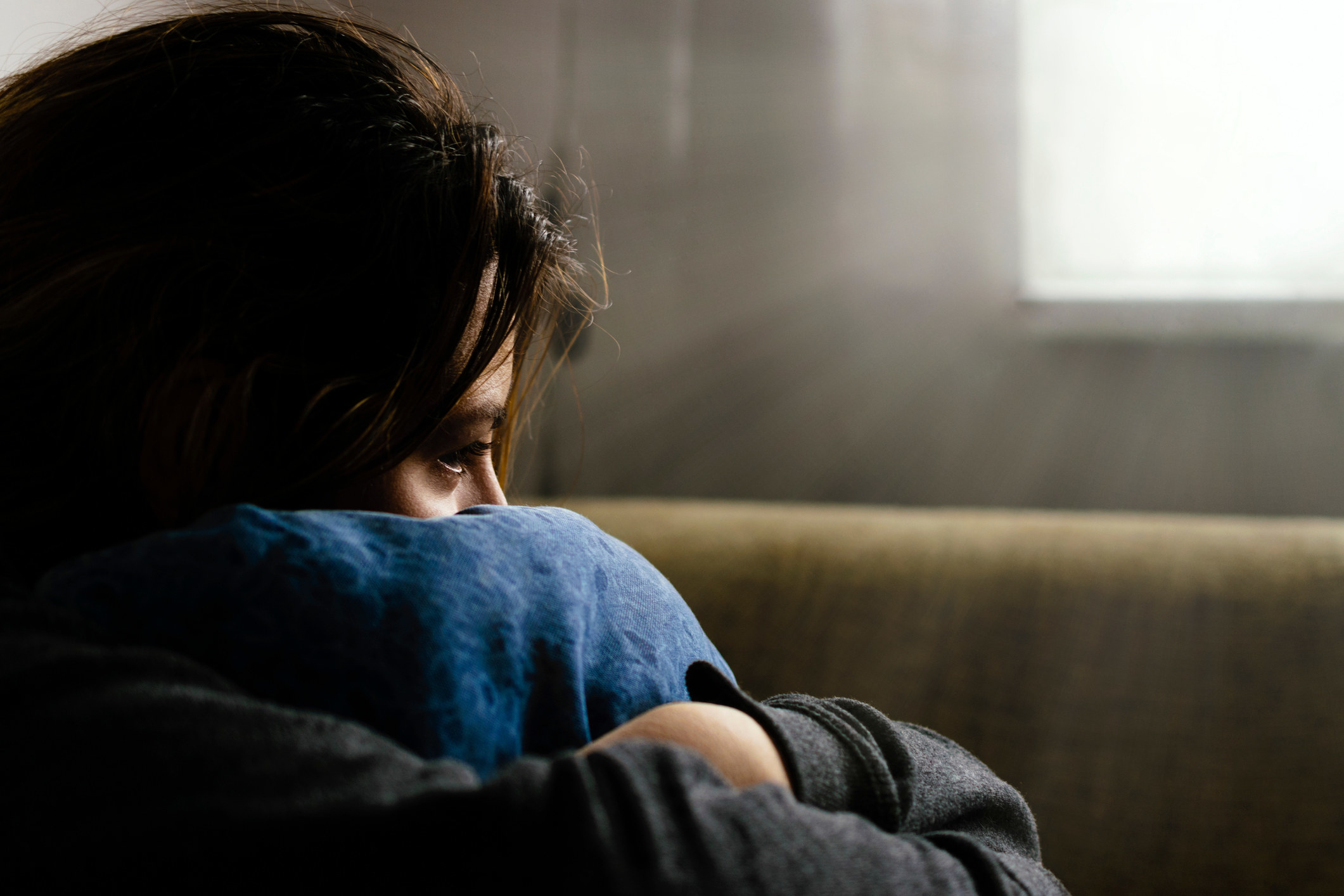 Person hugging a pillow and looking sad