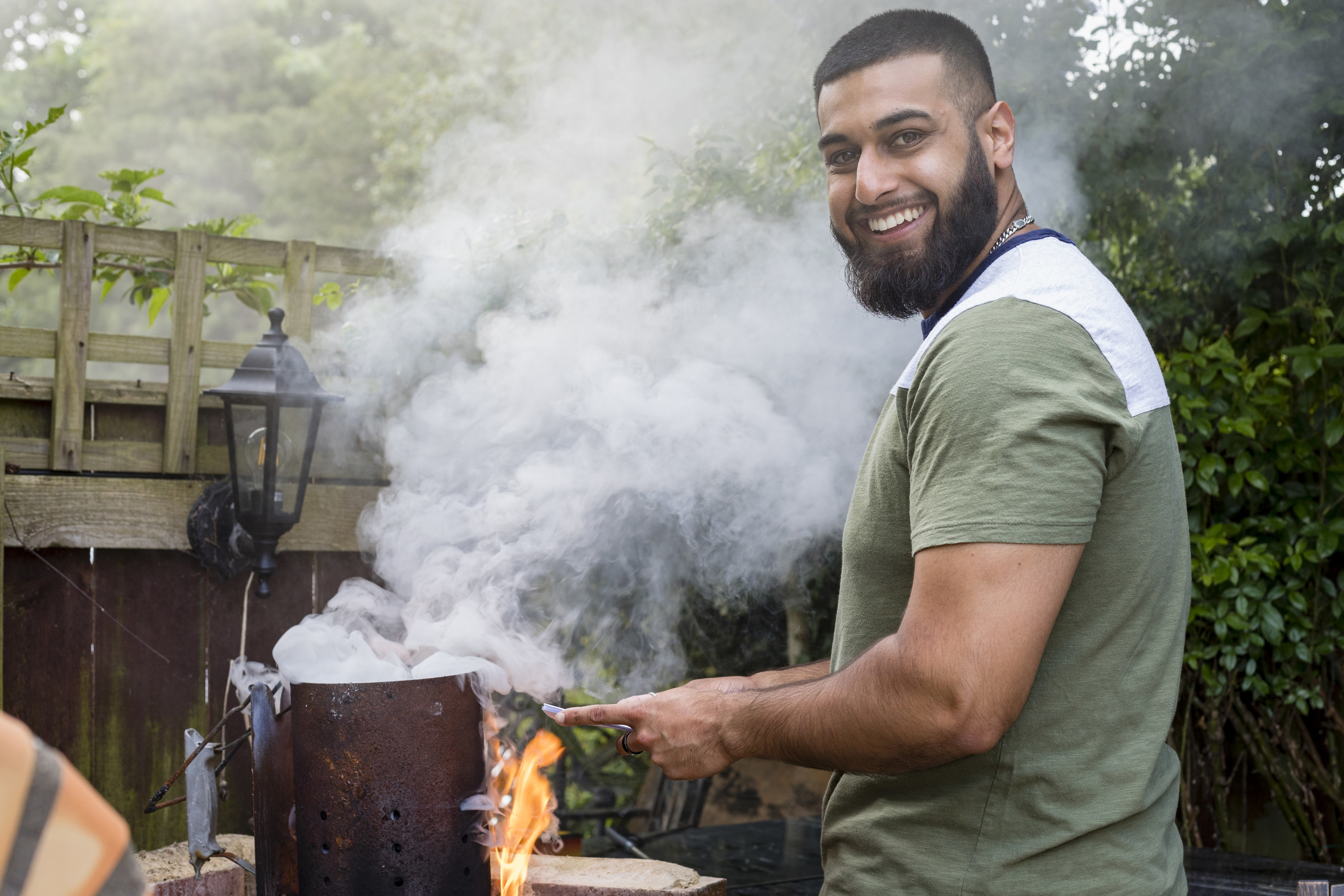 man grilling in his backyard with lots of smoke