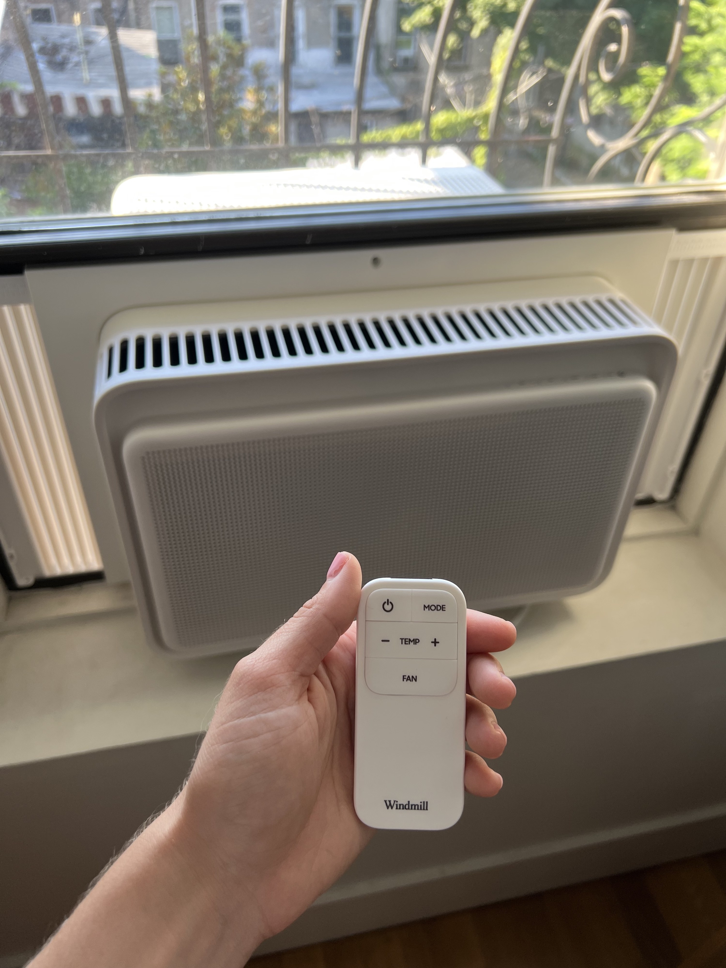 the window unit and a hand holding the remote