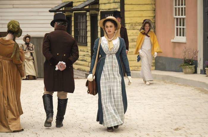 Rose williams as charlotte heywood walking through a period town setting in sanditon