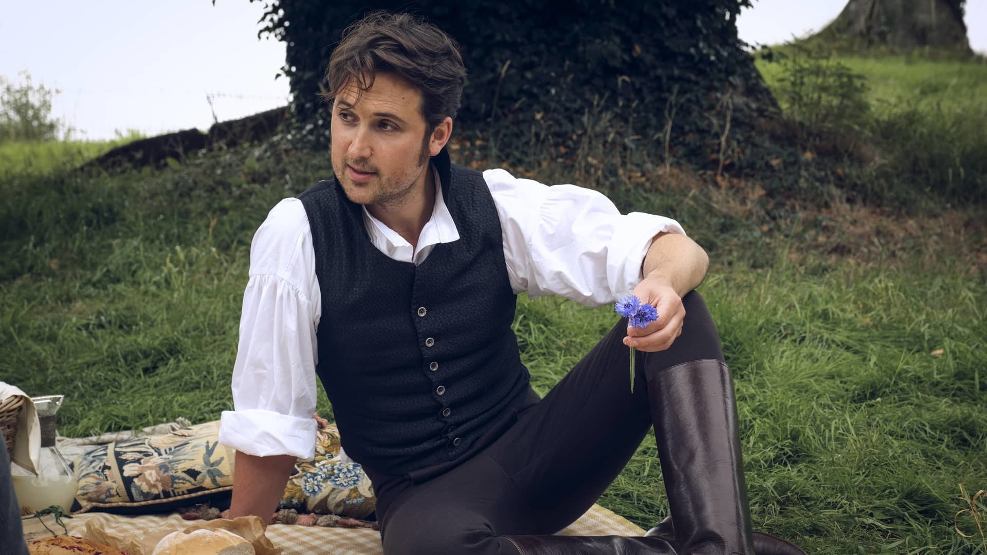 Ben lloyd hughes as alexander colbourne in period costume sitting at a picnic looking super hot