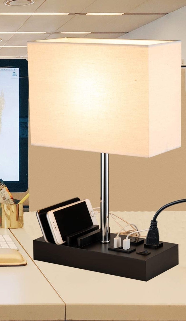 the lamp on a desk with phones plugged into it