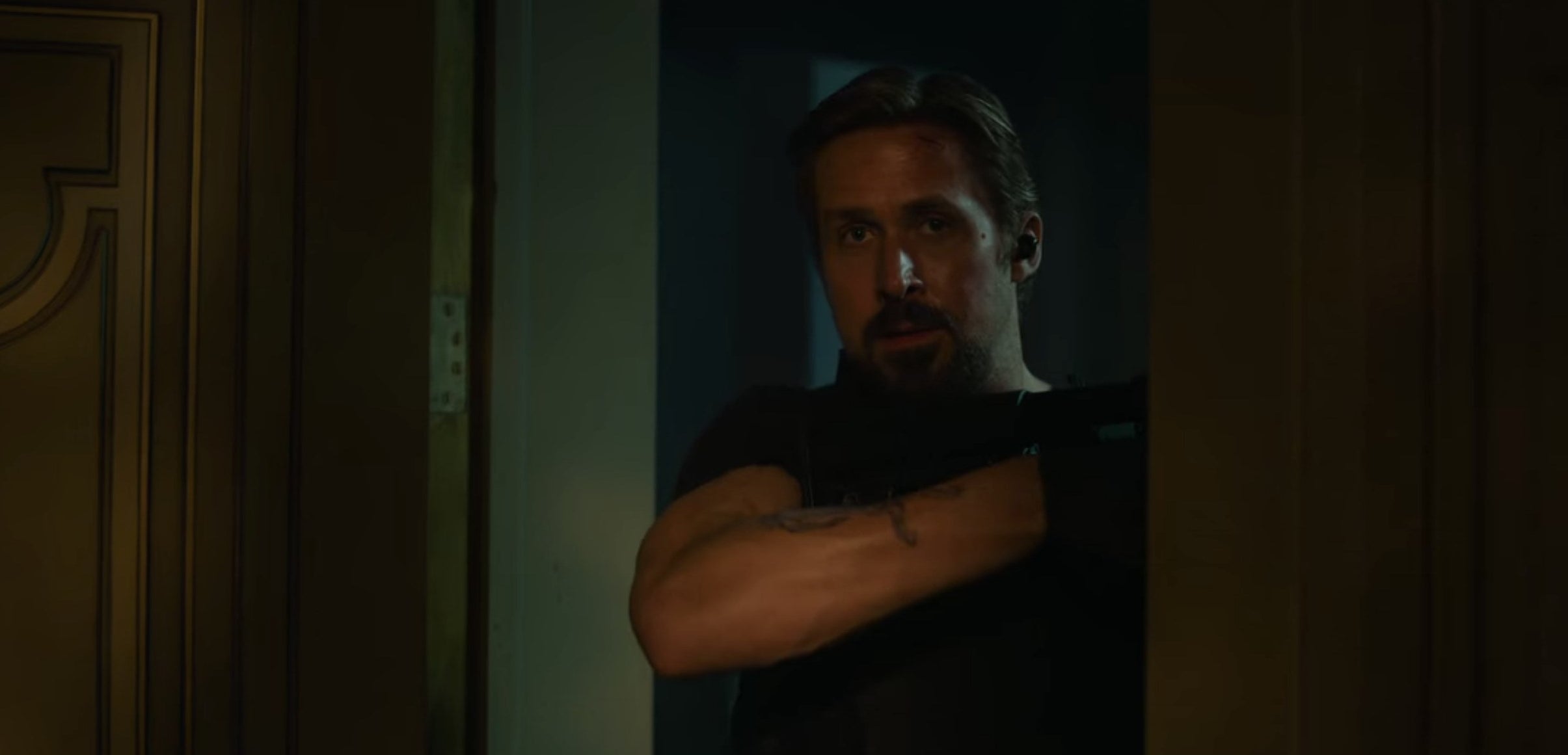 Six holding a gun and looking through a doorway in &quot;The Gray Man&quot;