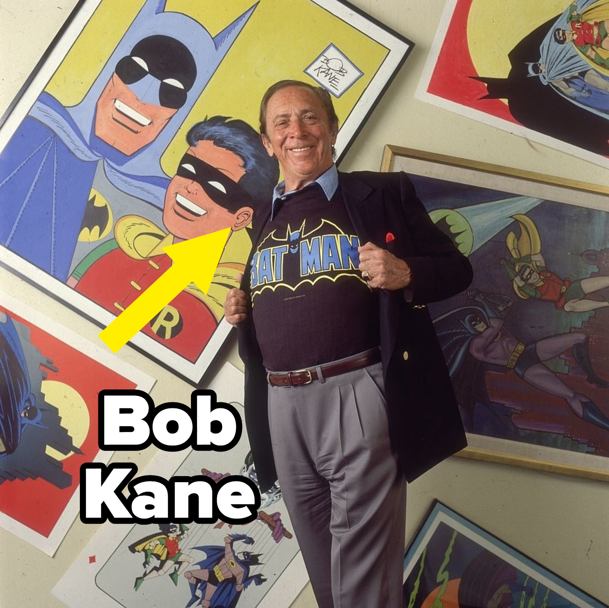 Bob Kane wearing a Batman T-shirt in front of a wall of Batman art