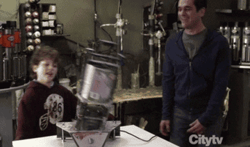 gif of luke and phil in modern family dancing beside a paint mixer