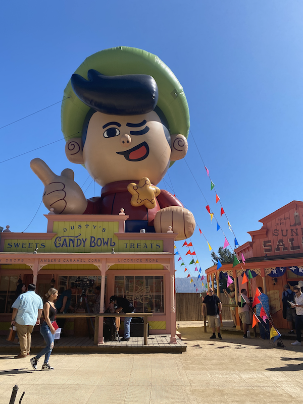 A closeup of the giant inflatable mascot near the entrance to town; you can now see it&#x27;s a sheriff character who is pointing and winking