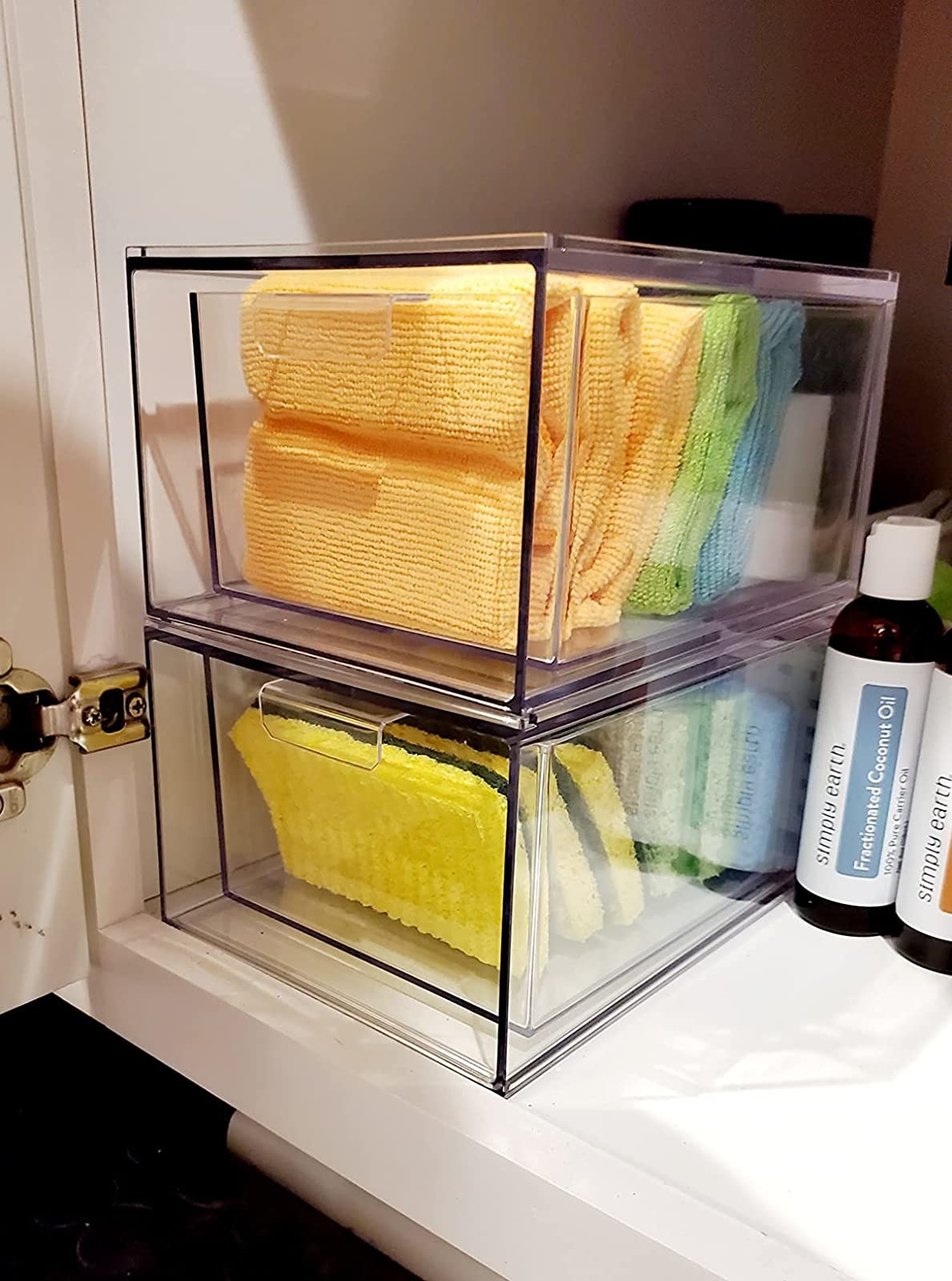 Reviewer&#x27;s clear drawers under the sink hold sponges and rags