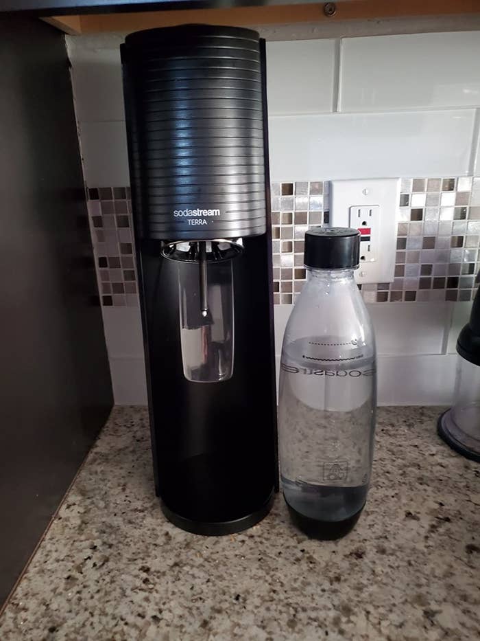 Reviewer&#x27;s photo of the sodastream on counter next to bottle