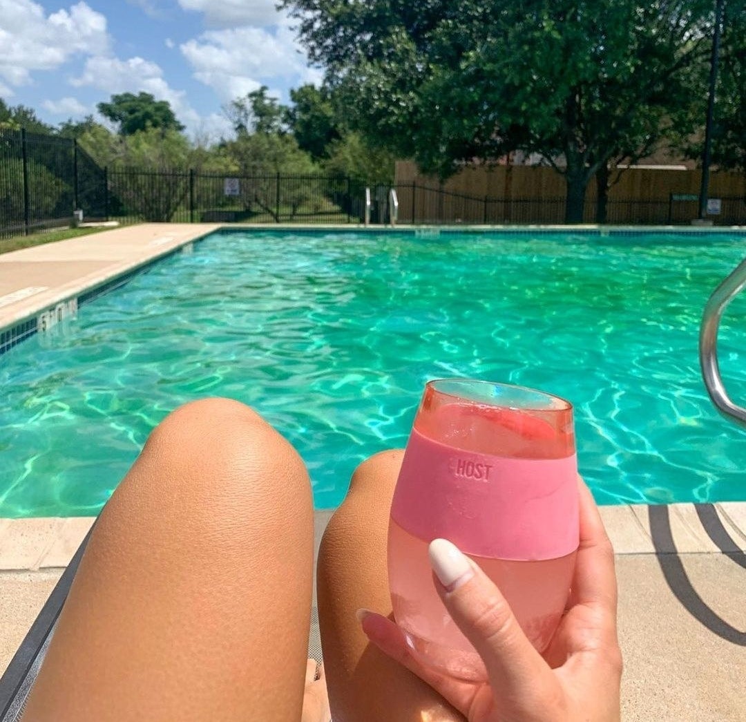 a person holding the gel-lined wine glass while relaxing by the pool