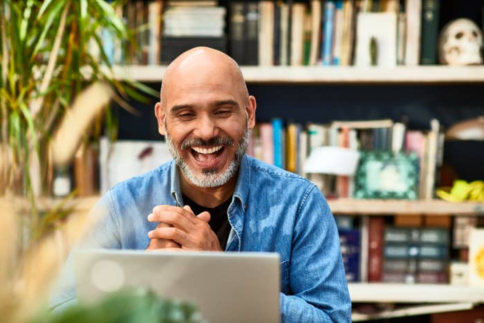 A man smiling at the laptop