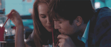 A man and woman sharing a drink with straws