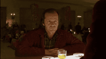 Jack Nicholson raising his eyebrows while sitting with a drink.