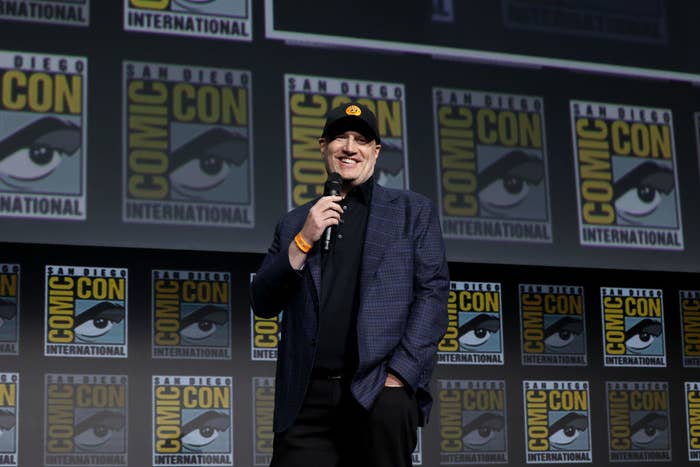 Kevin Feige smiles on stage while holding a microphone