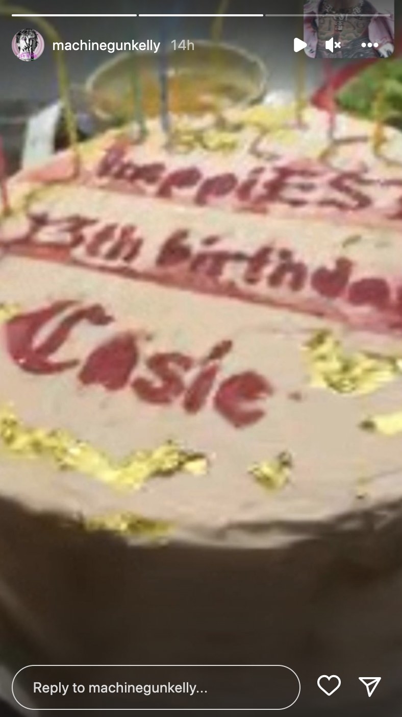 A FaceTime screenshot of a chocolate cake with gold details and MGK can be seen in the corner