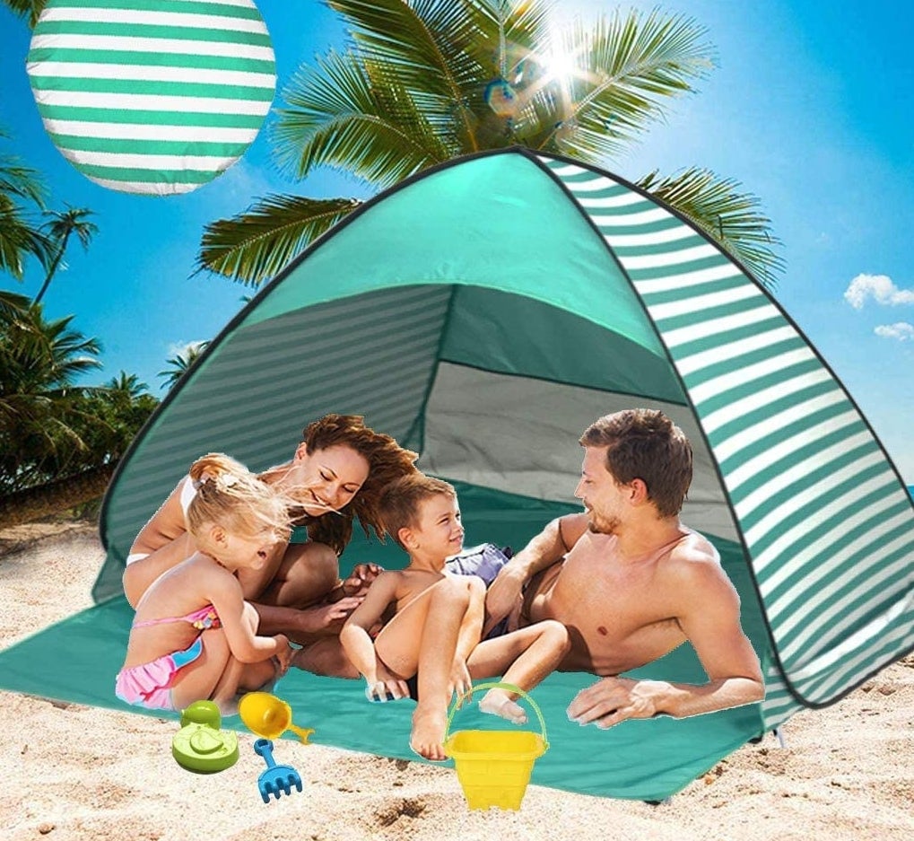 a family sitting in the sun shelter on the beach