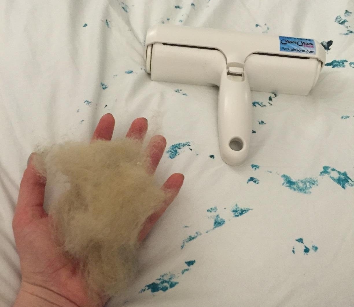 Reviewer holding a clump of cat hair in hand next to roller on the now spotless bed