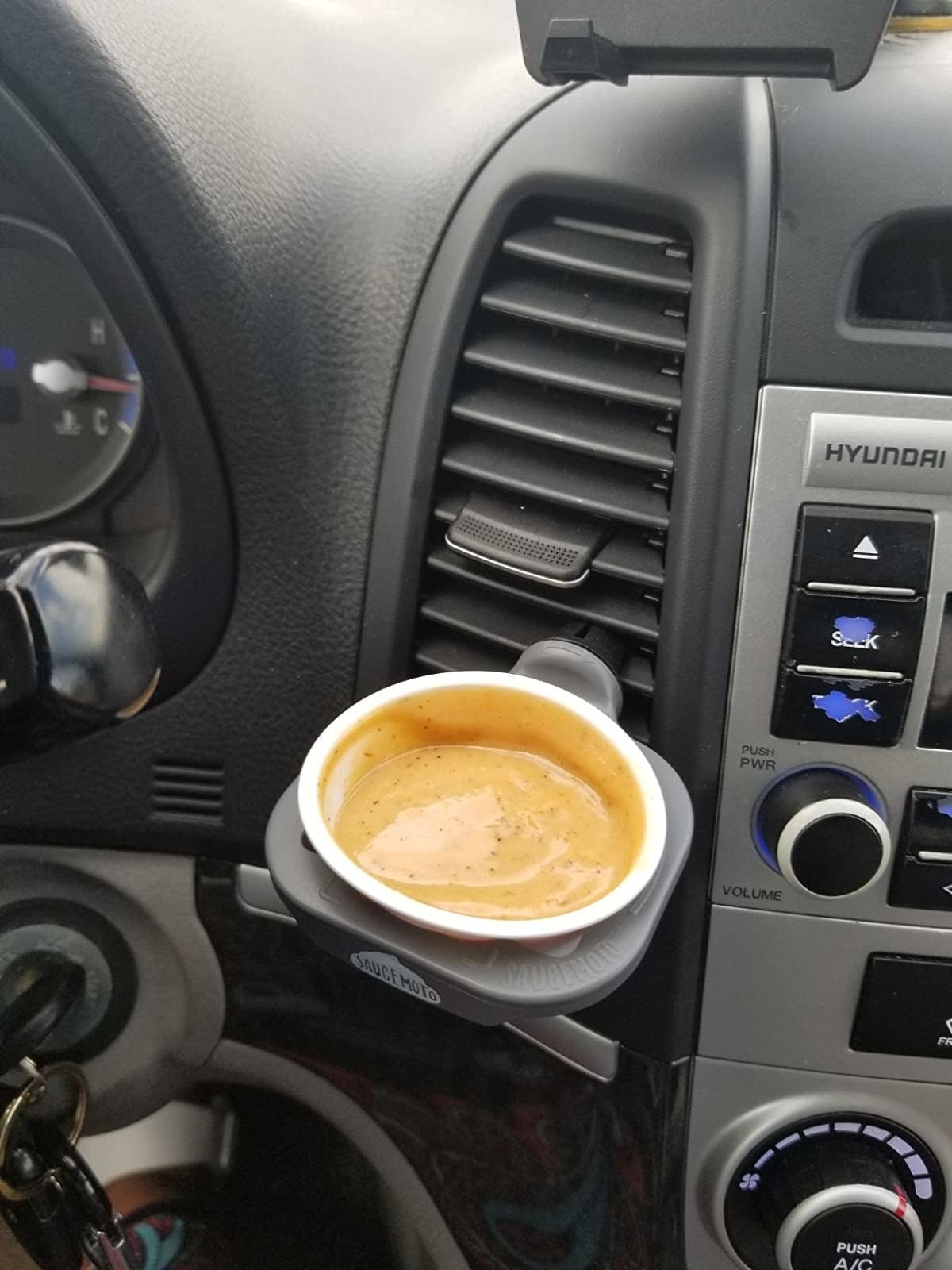 Reviewer's photo of the dip clip holding honey mustard in their car