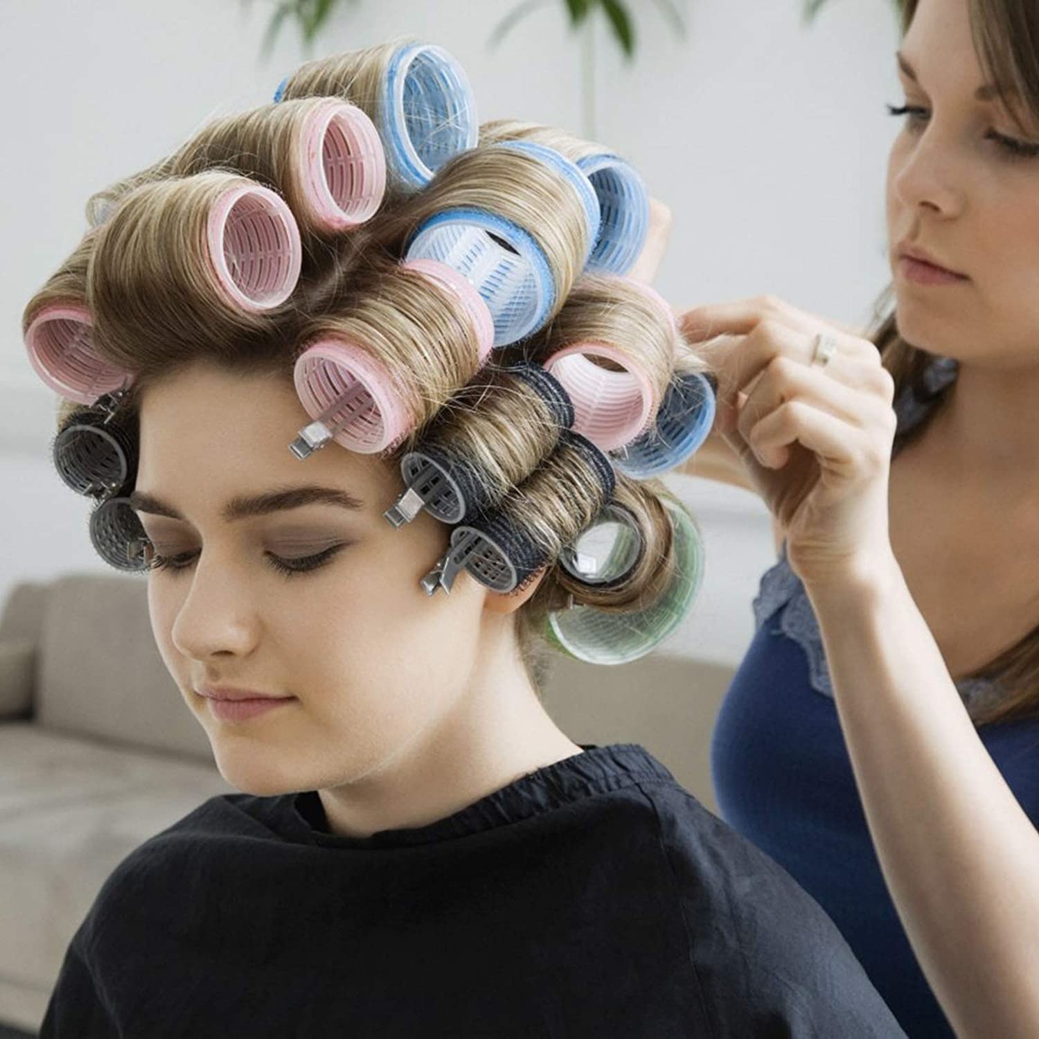 Someone sitting with the curlers in their hair while someone else puts them in