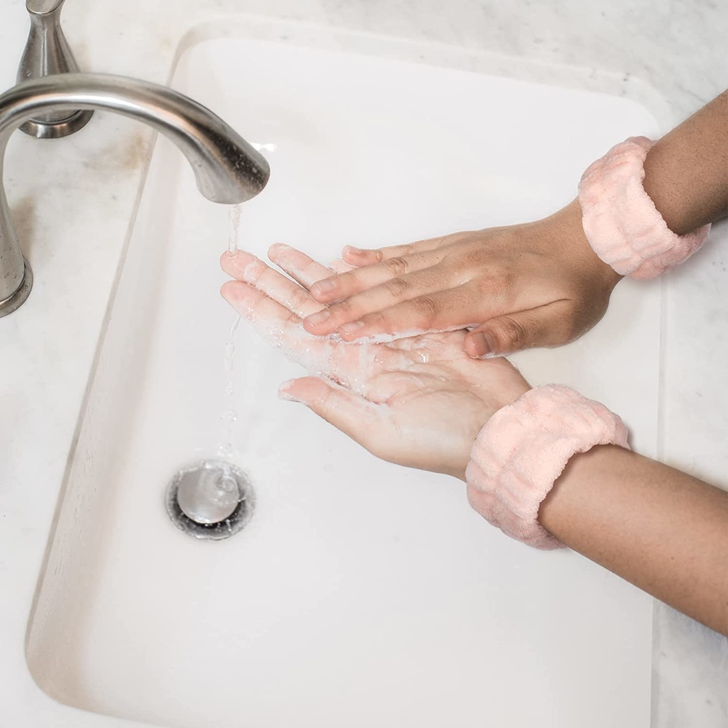 A person wearing the wristbands while washing their hands over a sink