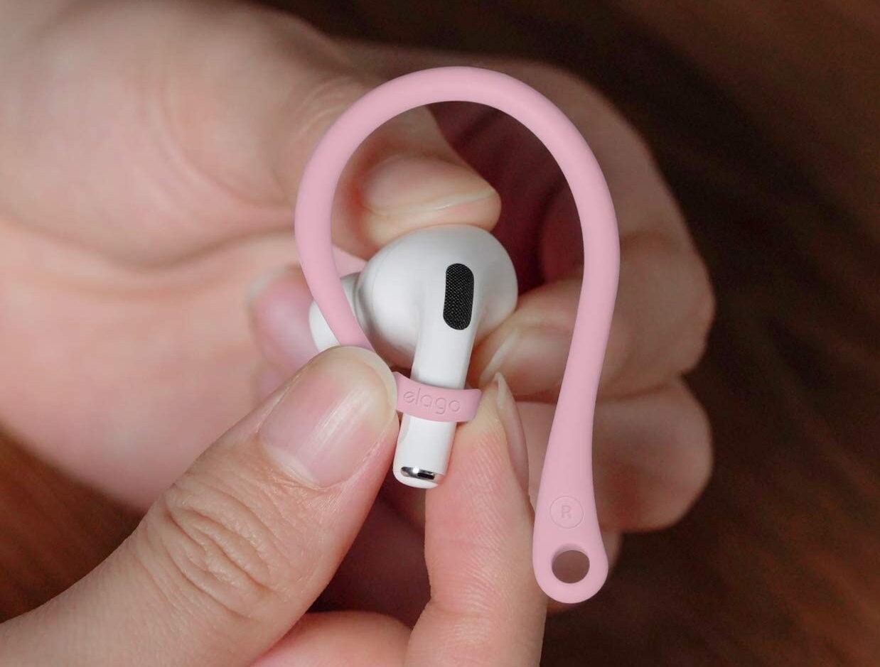 Someone holding an AirPod with the hook on it
