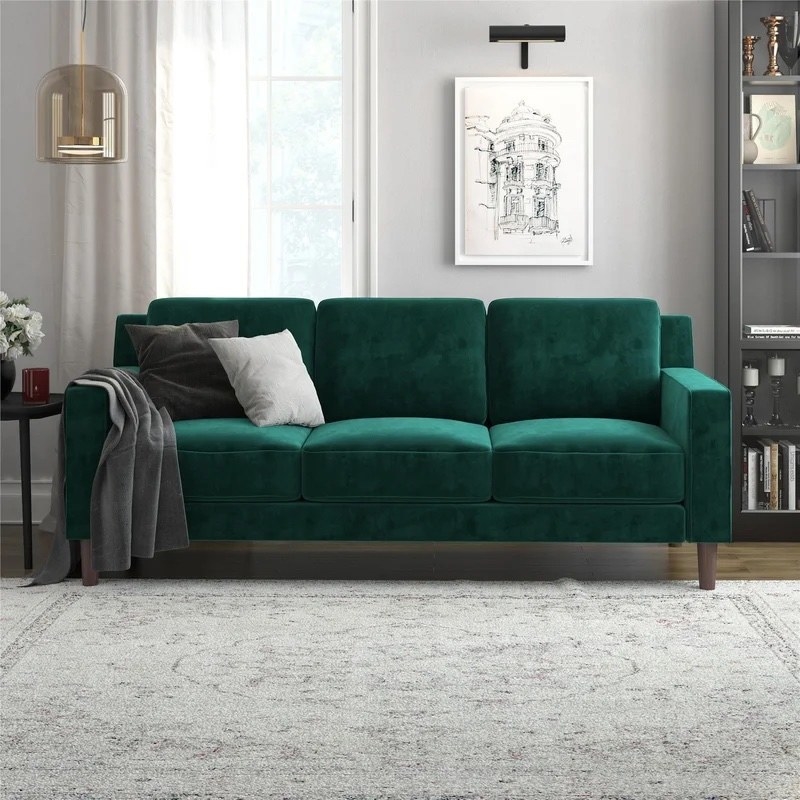 a green velvet square arm sofa in a living room