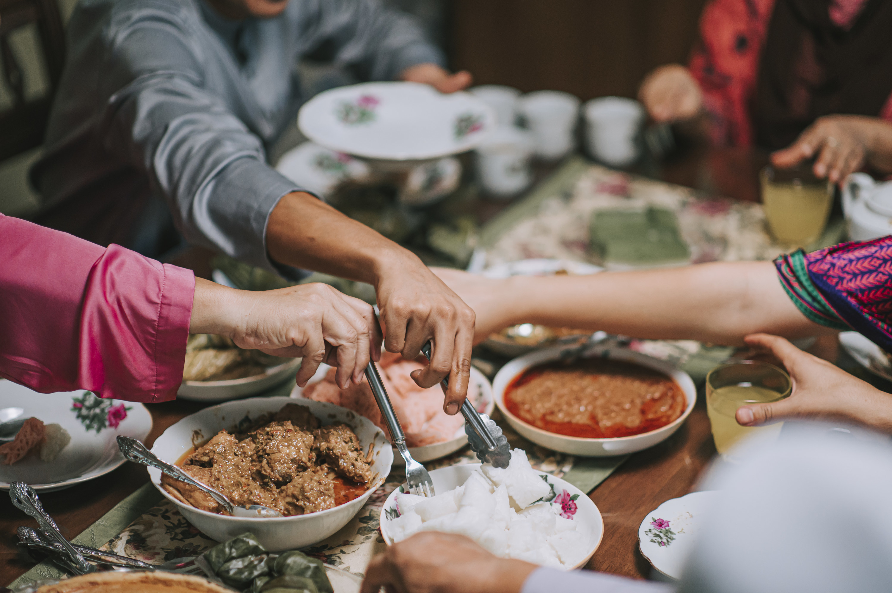 hands picking at food at a dinner table