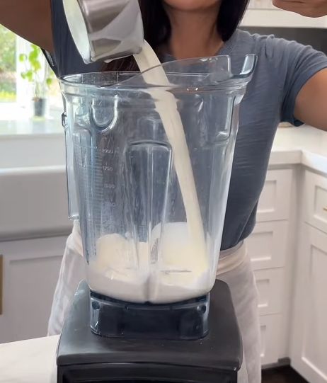 Pouring heavy cream into a large blender to whip it