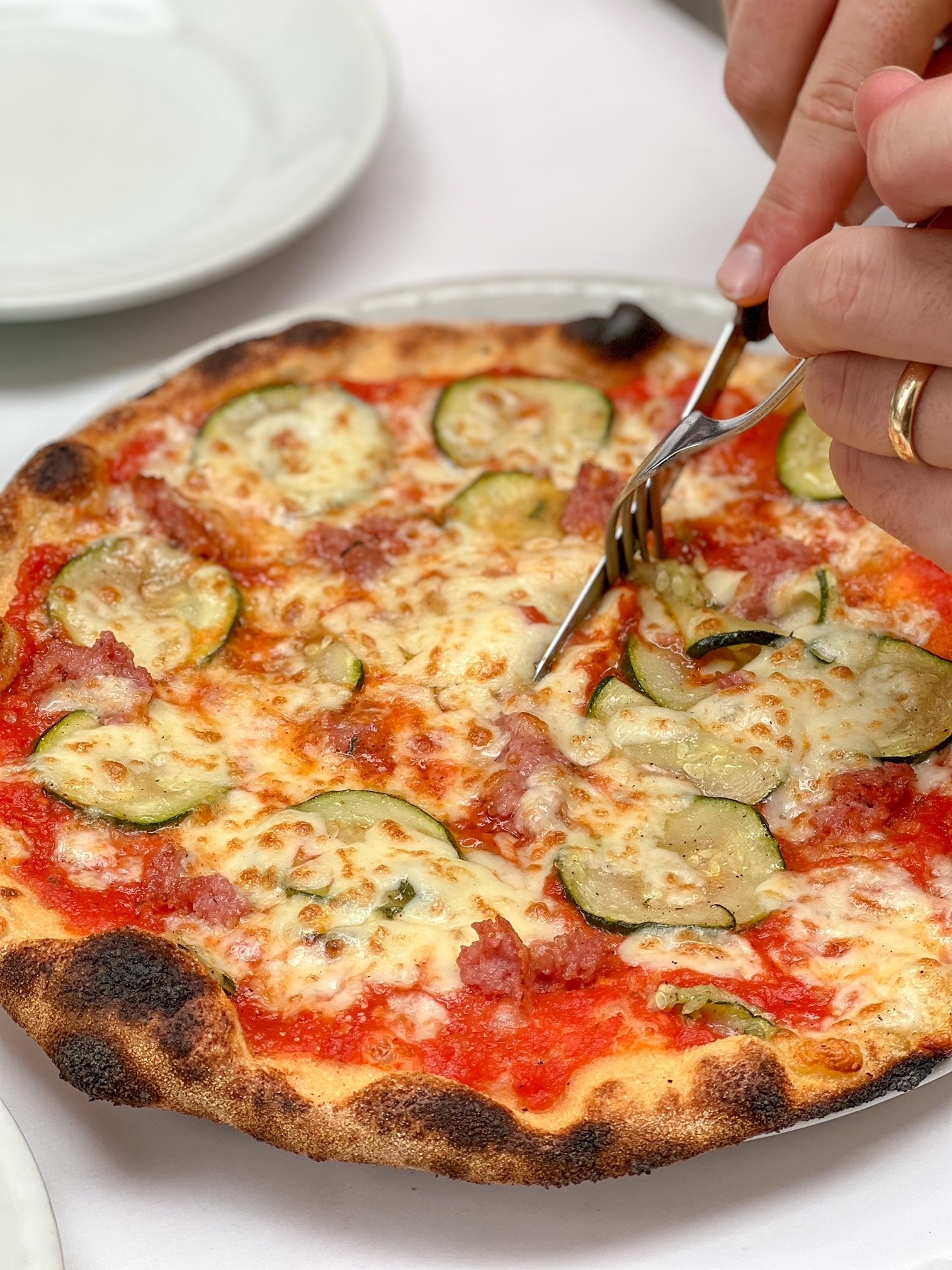 Slicing in pizza topped with cheese and zucchini.