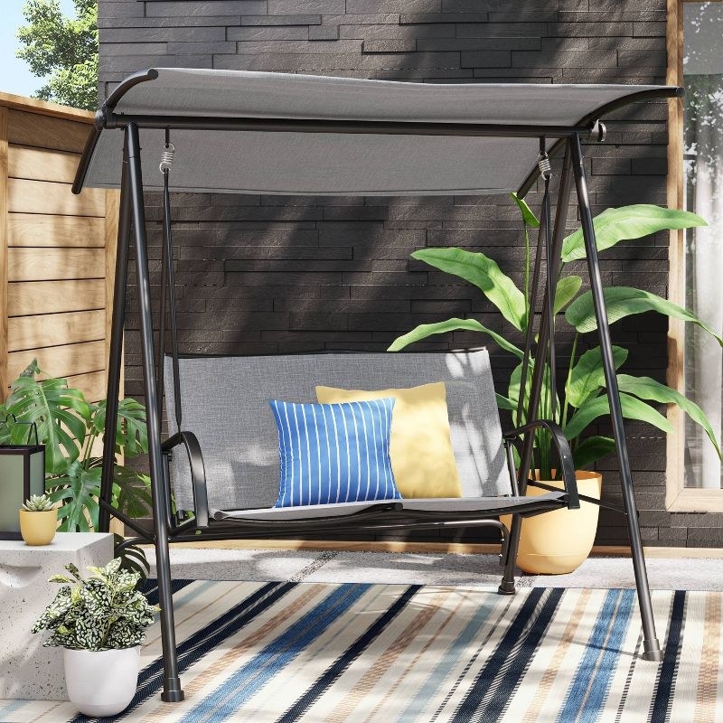 the black and gray porch swing with colorful throw pillows