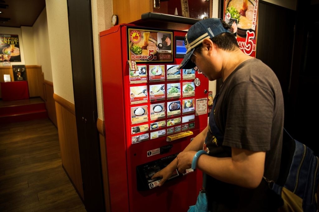 A man ordering ramen from a vending machine.