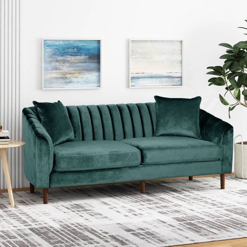 A teal contemporary velvet sofa in a living room